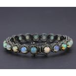 A white metal bangle set with cabochon opals and diamonds, dia. 7cm.