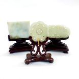Three carved celedon jade items on carved wooden stands. H 11cms