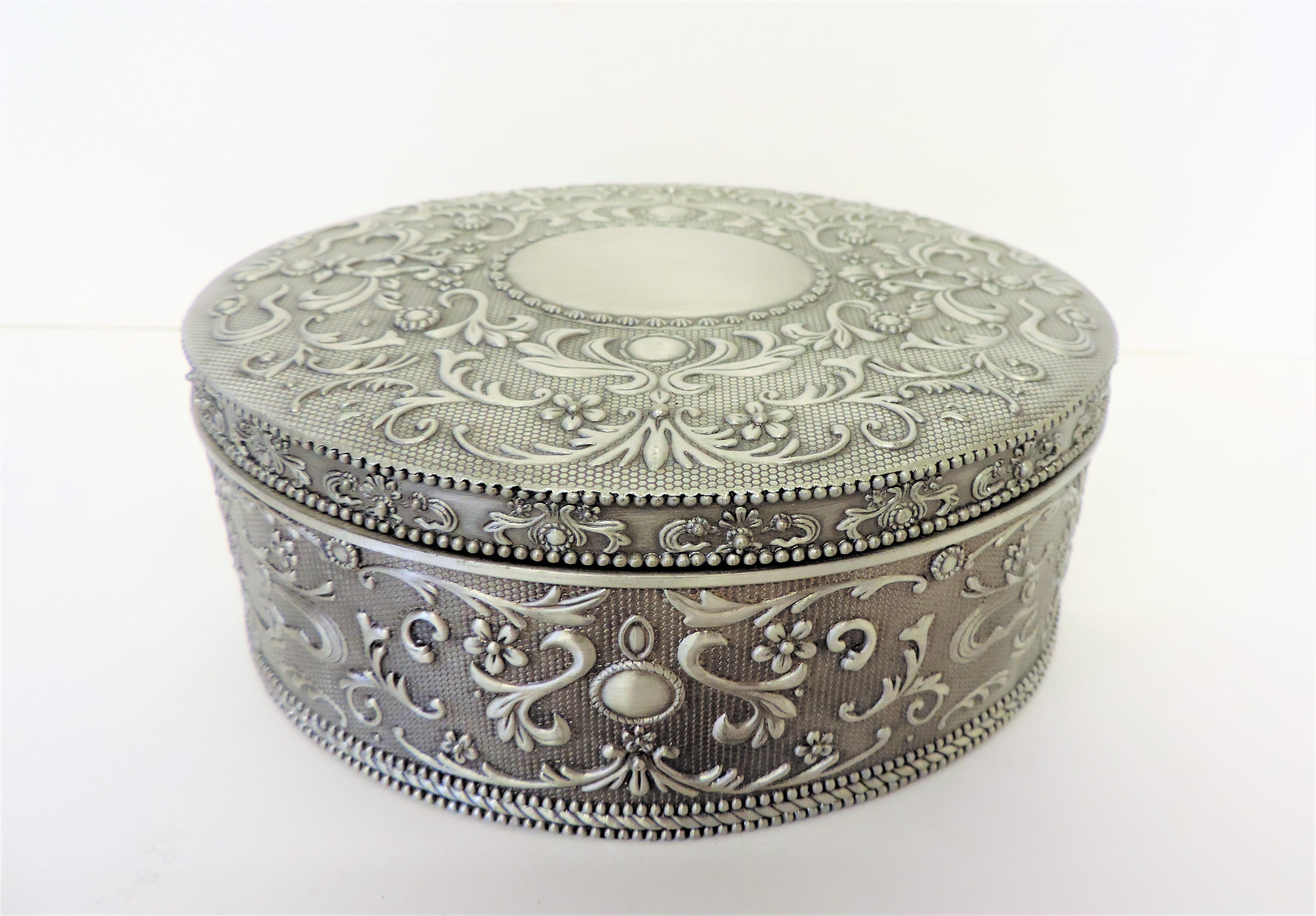 White Metal Velvet Lined Jewellery Box. An oval black velvet lined jewellery box measuring 16cm