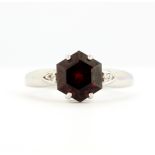 A 9ct white gold ring set with an hexagonal cut garnet and diamond set shoulders, (N).