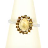 A 9ct white gold cluster ring set with a cabochon cut citrine surrounded by round cut citrines, (M.