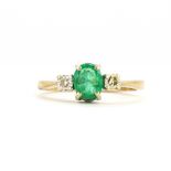 A 9ct yellow gold ring set with an oval cut emerald and diamonds, (I).