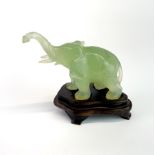 A Chinese carved jade elephant on a carved wooden stand, overall H. 8cm.