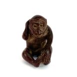 A signed, carved fruitwood figure of a monkey with an insect on its back, H. 5cm.