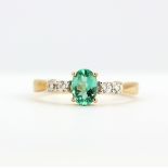 A 9ct yellow gold ring set with an oval cut green topaz and diamonds, (P).