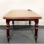 An early 20th Century oak wind out extendable dining table on castors with one leaf, unextended