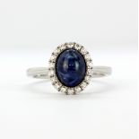 An 18ct white gold ring set with a cabochon cut sapphire and brilliant cut diamonds, (N).