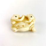 A signed carved bone model of two frogs on a lily pad, 4.5 x 4 x 2.5cm.