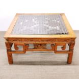 An oriental carved hardwood coffee table with plate glass top covering an interesting maze design,