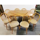 An Ercol blonde extendable dining table and two leaves with a set of eight Ercol 1960's beech and