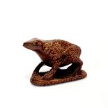 A carved fruitwood Netsuke of a frog with obsidian eyes and inset signature panel, H. 4cm, L. 6cm.