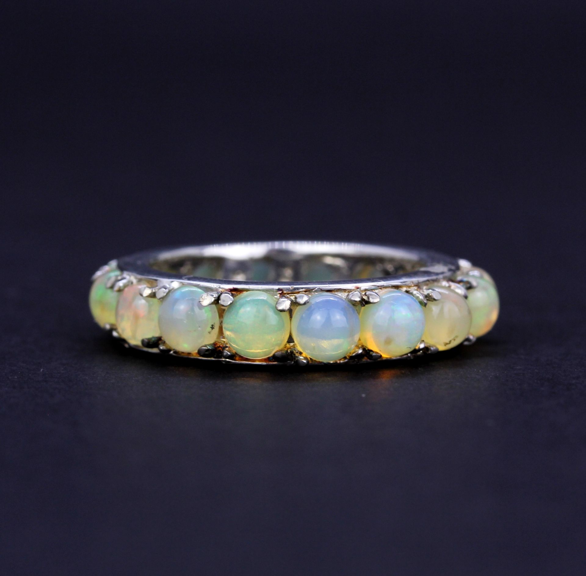 A 925 silver eternity ring set with round cabochon opals, approx. 2.97ct total, (N). With