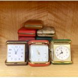 A group of ten vintage travel alarm clocks.