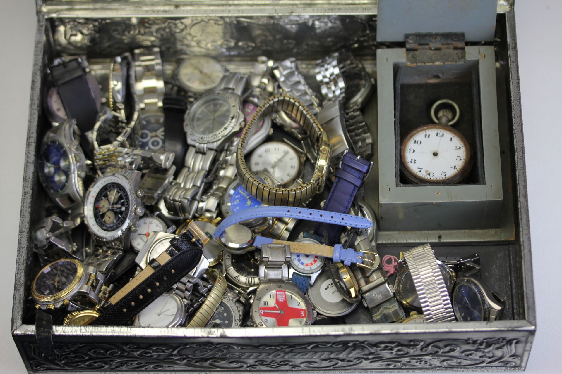 A vintage metal tin containing a quantity of mixed wristwatches inclusing a boxed pocketwatch.