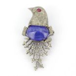 A large white metal bird shaped diamond set brooch with an oval cabochon tanzanite and a ruby set