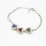 A 925 silver heart shaped bracelet set with oval cut emerald, sapphire and ruby and white stones, L.