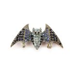 A white metal bat shaped brooch set with round cut sapphires, topaz and tanzanites, L. 3. 5cm.