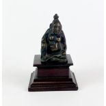 A small Eastern bronze figure of a seated deity on a later wooden plinth, H. 9.5cm.