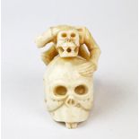 An Oriental carved bone skull and skeleton figure, L. 5cm. H.4cm.