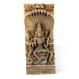 An Indonesian carved wooden figure of a Hindu Deity with Naga background, H. 54cm.