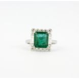 An 18ct white gold ring set with an emerald cut emerald, 1 x 0.8cm, approx. 3.75ct, surrounded by