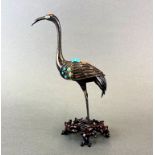 A Chinese enamelled and gilt white metal (tested silver) figure of a crane, inset with coral and
