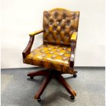 A button backed leather upholstered swivel desk chair.