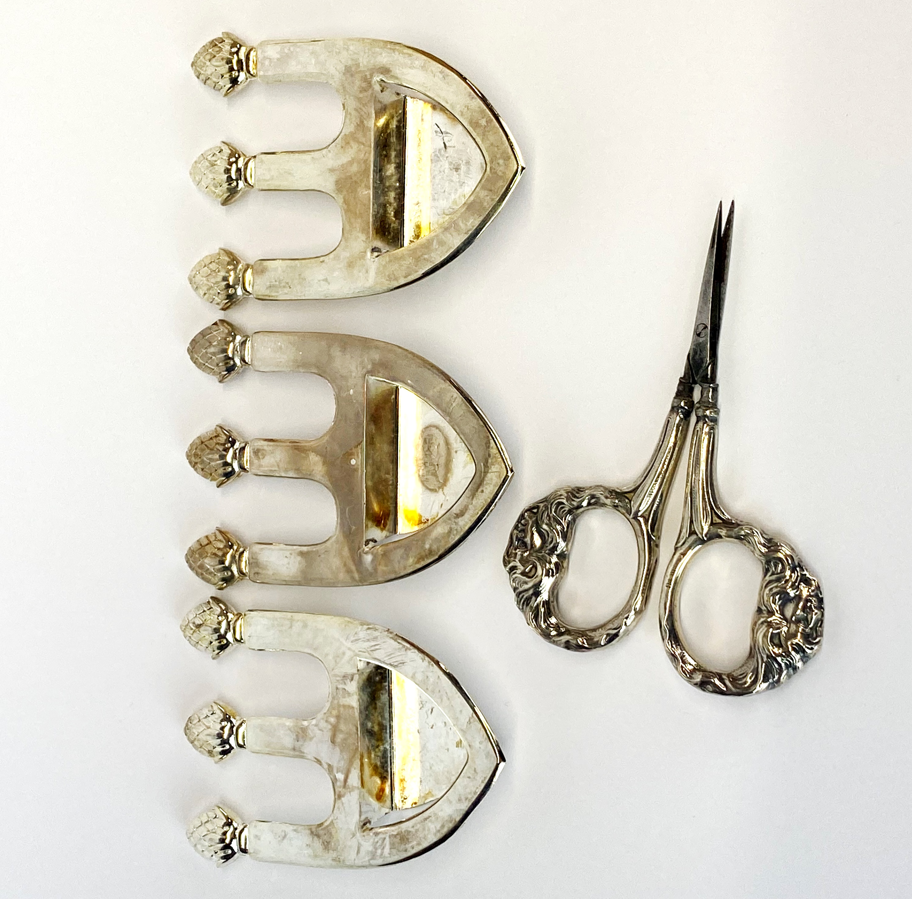 A pair of sterling silver handled scissors with a group of three silver plated menu holders.