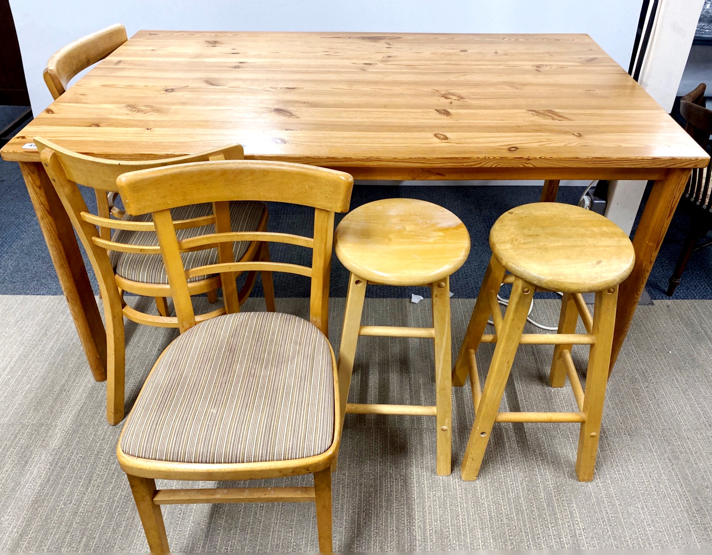 A pine kitchen table, 86 x 150cm, with three kitchen chairs and two stools.