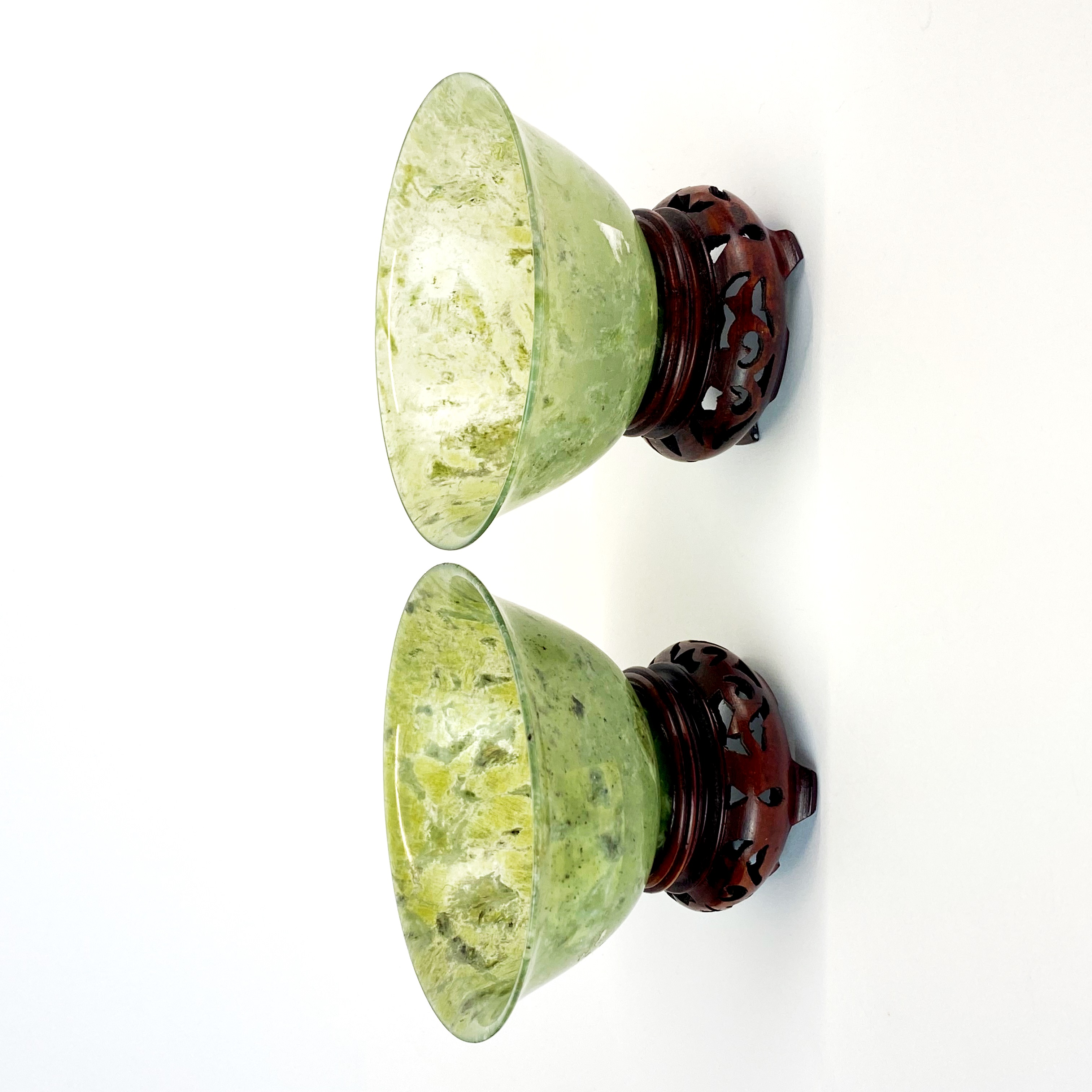 A pair of fine Chinese spinach jade bowls with carved wooden stands, Dia. 10cm.