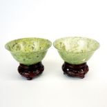 A pair of fine Chinese spinach jade bowls with carved wooden stands, Dia. 10cm.