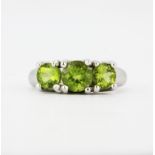 A hallmarked 9ct white gold ring set with round cut peridots, (N.5).