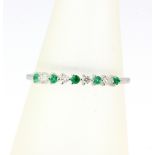 An 18ct white gold half eternity ring set with emeralds and diamonds, (L.5).