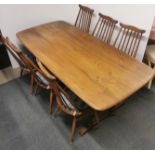 A golden Ercol dining table together with a set of six spindle back dining chairs, table 180 x 85