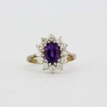 A hallmarked 9ct yellow gold ring set with an oval cut amethyst surrounded by white topaz, (K.5).