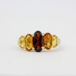 A hallmarked 9ct yellow gold ring set with oval cut garnet and graduated colour citrines, (Q.5).