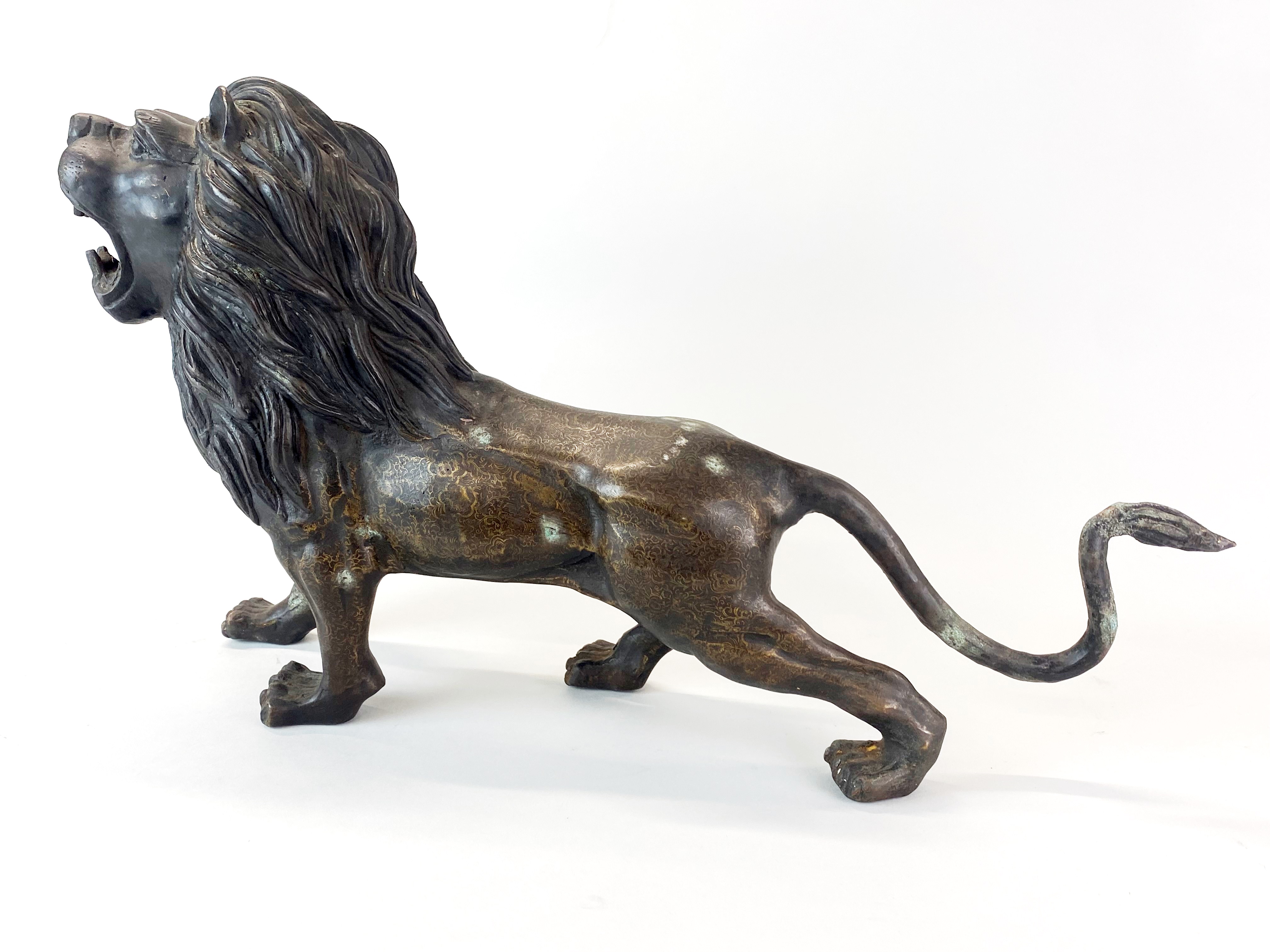 A large bronze figure of a roaring lion with interesting surface decoration, H. 31cm, L. 56cm.