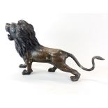 A large bronze figure of a roaring lion with interesting surface decoration, H. 31cm, L. 56cm.