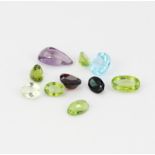 An assortment of mixed cut unmounted gemstones including peridot, amethyst and aquamarine.