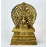 A Tibetan gilt bronze temple style figure of a seated Buddha on an elevated plinth, H. 28cm.