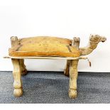 A mid 20th century carved wooden folding camel saddle stool with leather cushion, L. 87cm, H. 50cm.