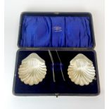 A cased set of hallmarked silver shell shaped butter dishes and butter knives.