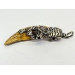 A Tibetan silvered bronze tiger amulet with carved bone 'claw' L. 12.5cm.