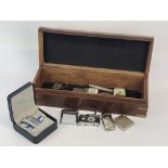 A wooden box containing a quantity of vintage lighters.