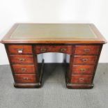 A stained oak and leather topped, ten drawer knee hole writing desk with an interesting hidden