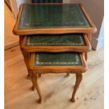 A carved light wood, leather topped nest of three tables with protective plate glass tops, 53 x