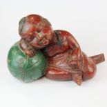 A mid 20th century painted Chinese hardwood figure of a boy resting on a melon, H. 23cm.