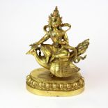 A lovely Tibetan gilt bronze figure of a Deity seated on a bird, H. 24cm.