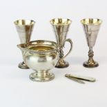 A hallmarked silver milk jug with three hallmarked silver kiddish cups and a mother of pearl and