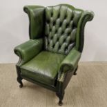 A chesterfield green leather wingback armchair, H. 104cm.
